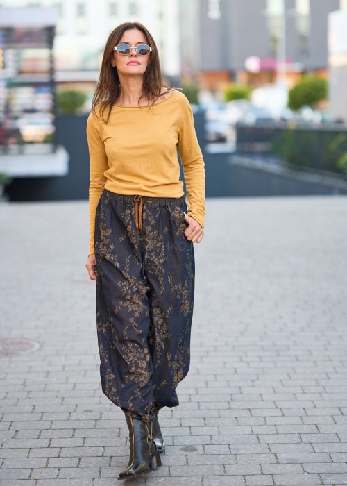 Ciemnogranatowe spodnie z szerokimi nogawkami, zdobione złotym roślinnym wzorem, zakończone gumką przy kostkach.