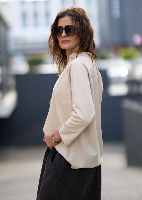 Beżowa koszula damska z długim rękawem i dekoltem zapinanym na guziki, wykonana z lekkiej tkaniny o luźnym kroju