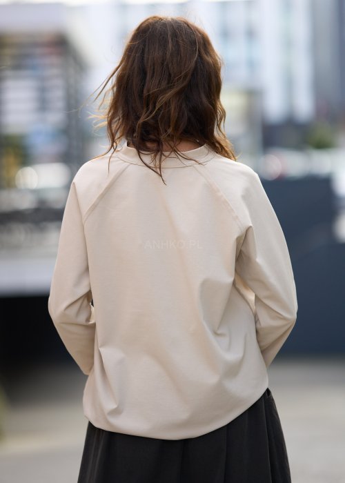 Beżowa koszula damska z długim rękawem i dekoltem zapinanym na guziki, wykonana z lekkiej tkaniny o luźnym kroju