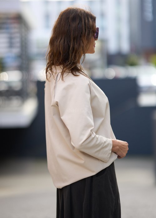 Beżowa koszula damska z długim rękawem i dekoltem zapinanym na guziki, wykonana z lekkiej tkaniny o luźnym kroju