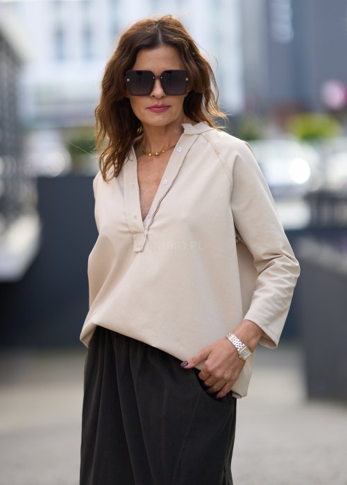 Beżowa koszula damska z długim rękawem i dekoltem zapinanym na guziki, wykonana z lekkiej tkaniny o luźnym kroju