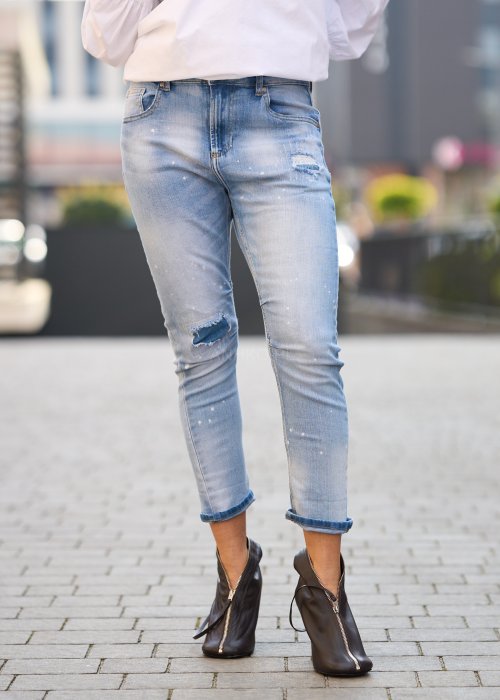 Jasnoniebieskie jeansy z przetarciami i dziurami na kolanach