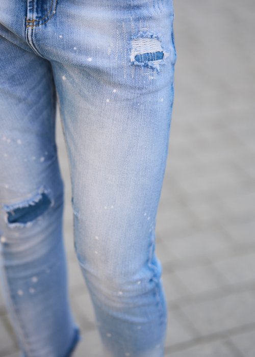 Jasnoniebieskie jeansy z przetarciami i dziurami na kolanach