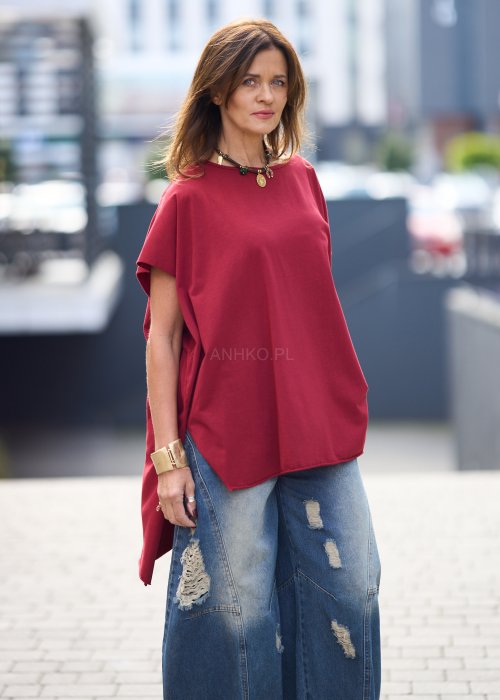 Bordowa bluzka oversize z asymetrycznym dołem i wydłużonym tyłem, zestawiona z jasnymi jeansami. Luźny fason i gładki materiał nadają stylizacji nowoczesny, miejski charakter.