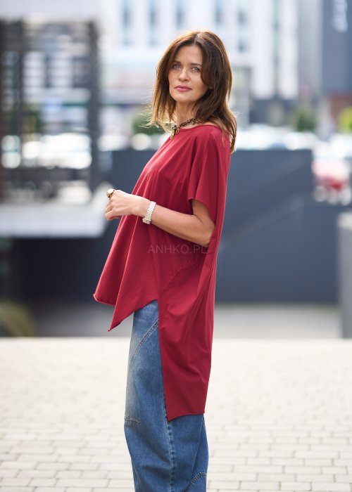 Bordowa bluzka oversize z asymetrycznym dołem i wydłużonym tyłem, zestawiona z jasnymi jeansami. Luźny fason i gładki materiał nadają stylizacji nowoczesny, miejski charakter.