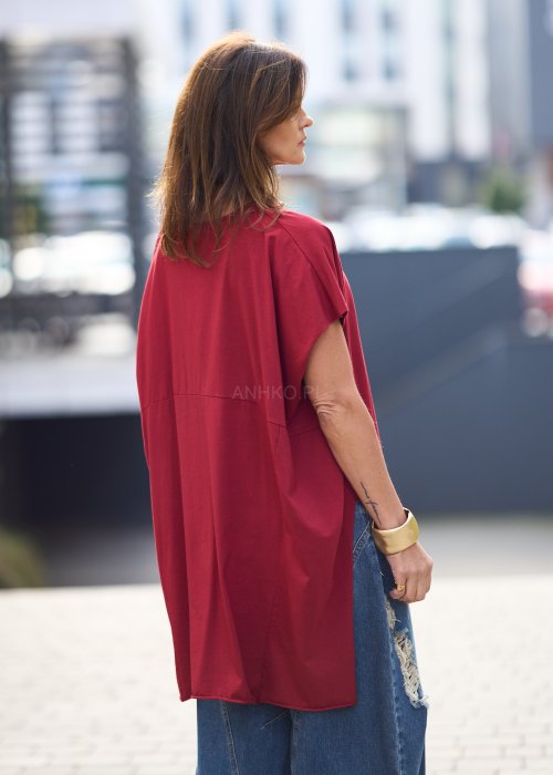 Bordowa bluzka oversize z asymetrycznym dołem i wydłużonym tyłem, zestawiona z jasnymi jeansami. Luźny fason i gładki materiał nadają stylizacji nowoczesny, miejski charakter.