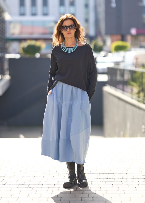 Czarna bluzka oversize z długim rękawem i szerokim dekoltem, zestawiona z jasnoniebieską spódnicą w nowoczesnej, miejskiej stylizacji.