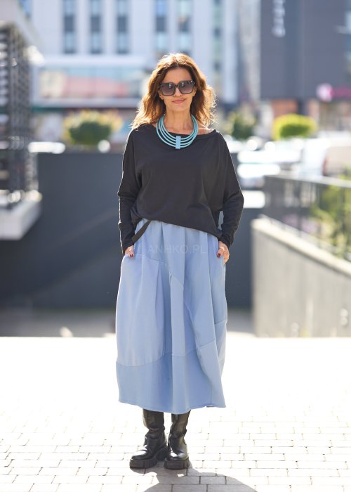 Czarna bluzka oversize z długim rękawem i szerokim dekoltem, zestawiona z jasnoniebieską spódnicą w nowoczesnej, miejskiej stylizacji.