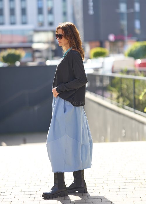 Czarna bluzka oversize z długim rękawem i szerokim dekoltem, zestawiona z jasnoniebieską spódnicą w nowoczesnej, miejskiej stylizacji.