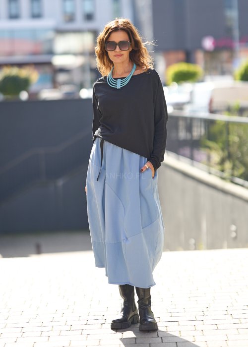 Czarna bluzka oversize z długim rękawem i szerokim dekoltem, zestawiona z jasnoniebieską spódnicą w nowoczesnej, miejskiej stylizacji.