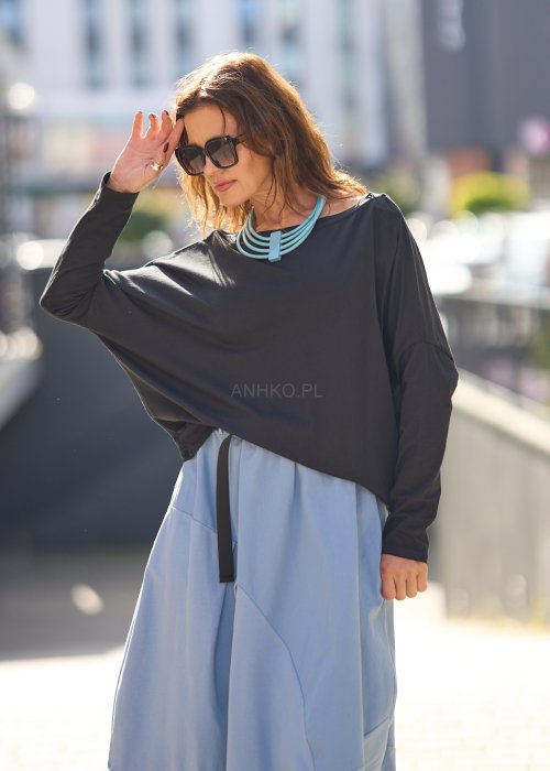 Czarna bluzka oversize z długim rękawem i szerokim dekoltem, zestawiona z jasnoniebieską spódnicą w nowoczesnej, miejskiej stylizacji.