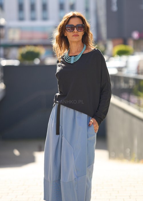 Czarna bluzka oversize z długim rękawem i szerokim dekoltem, zestawiona z jasnoniebieską spódnicą w nowoczesnej, miejskiej stylizacji.