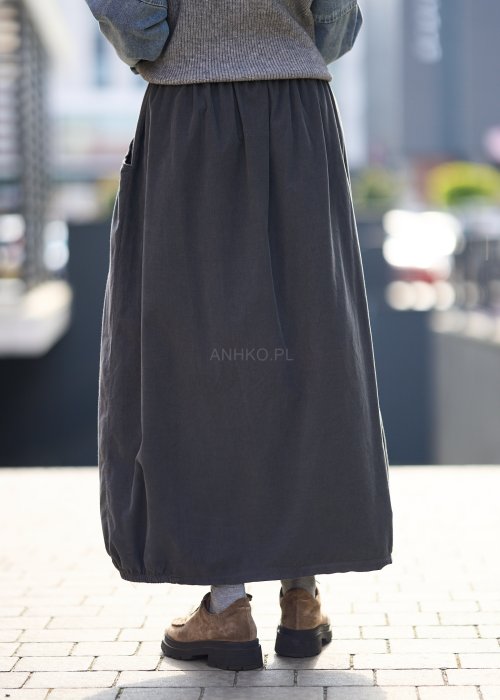 Grafitowa spódnica maxi z elastyczną talią i kieszeniami, o luźnym kroju, zestawiona z krótkim swetrem i brązowymi półbutami w miejskiej stylizacji.