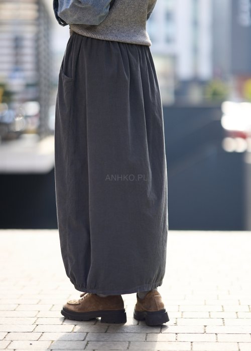 Grafitowa spódnica maxi z elastyczną talią i kieszeniami, o luźnym kroju, zestawiona z krótkim swetrem i brązowymi półbutami w miejskiej stylizacji.