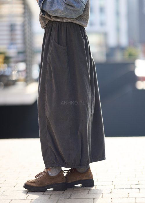 Grafitowa spódnica maxi z elastyczną talią i kieszeniami, o luźnym kroju, zestawiona z krótkim swetrem i brązowymi półbutami w miejskiej stylizacji.