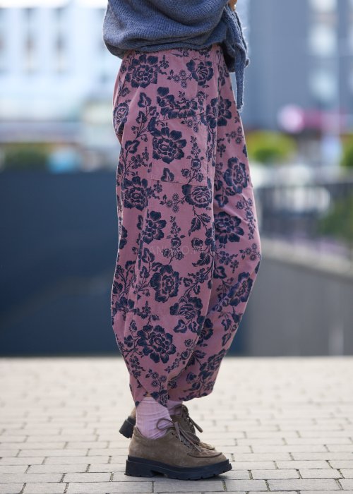 Różowe spodnie damskie z luźną nogawką i czarnym kwiatowym wzorem, wykonane z lekkiego materiału z kieszeniami
