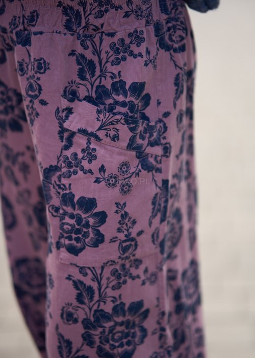 Różowe spodnie damskie z luźną nogawką i czarnym kwiatowym wzorem, wykonane z lekkiego materiału z kieszeniami