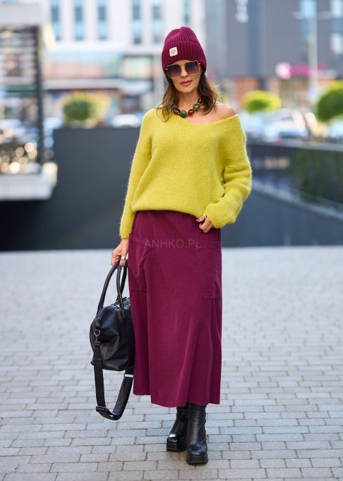 Śliwkowa spódnica sztruksowa midi z naszywanymi kieszeniami i elastycznym pasem, zestawiona z limonkowym swetrem i czarnymi botkami w miejskiej stylizacji.