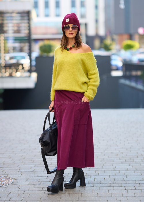 Śliwkowa spódnica sztruksowa midi z naszywanymi kieszeniami i elastycznym pasem, zestawiona z limonkowym swetrem i czarnymi botkami w miejskiej stylizacji.