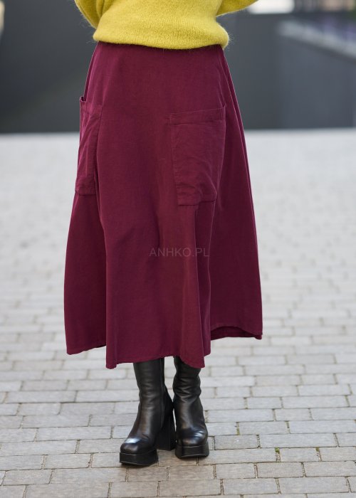 Śliwkowa spódnica sztruksowa midi z naszywanymi kieszeniami i elastycznym pasem, zestawiona z limonkowym swetrem i czarnymi botkami w miejskiej stylizacji.