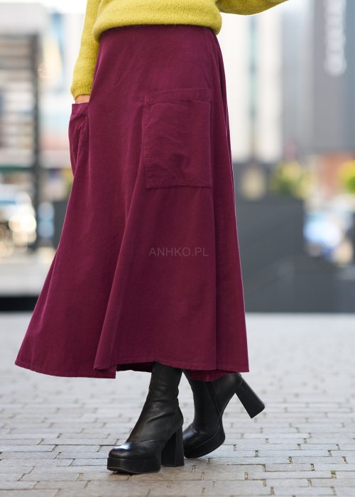 Śliwkowa spódnica sztruksowa midi z naszywanymi kieszeniami i elastycznym pasem, zestawiona z limonkowym swetrem i czarnymi botkami w miejskiej stylizacji.