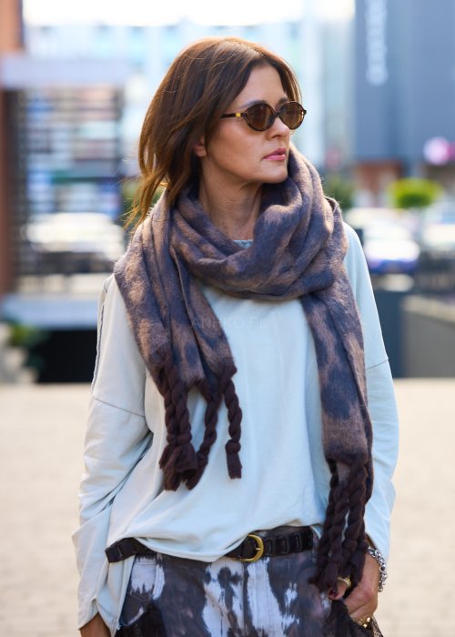 Miękki szal z motywem panterki, zakończony grubymi, plecionymi frędzlami.