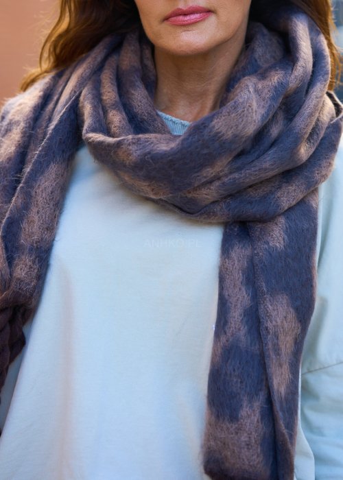 Miękki szal z motywem panterki, zakończony grubymi, plecionymi frędzlami.