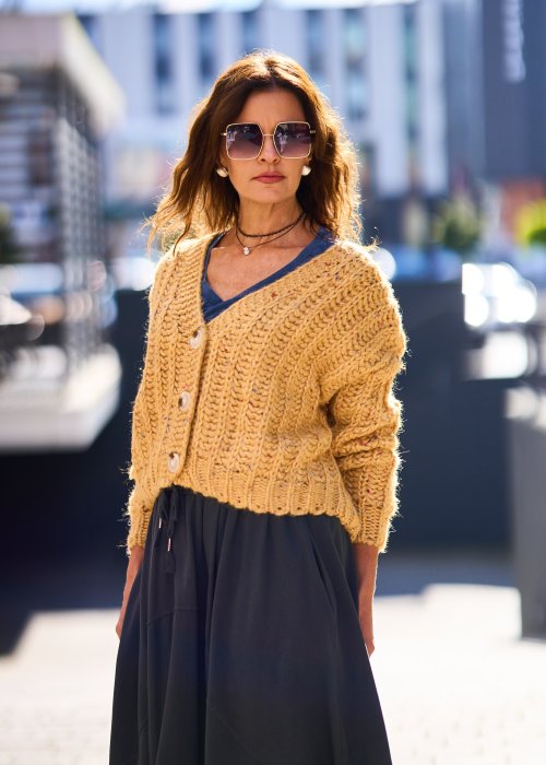 Żółty kardigan damski z grubym splotem, zapinany na duże guziki, o krótszym kroju i luźnym fasonie, styl casual boho