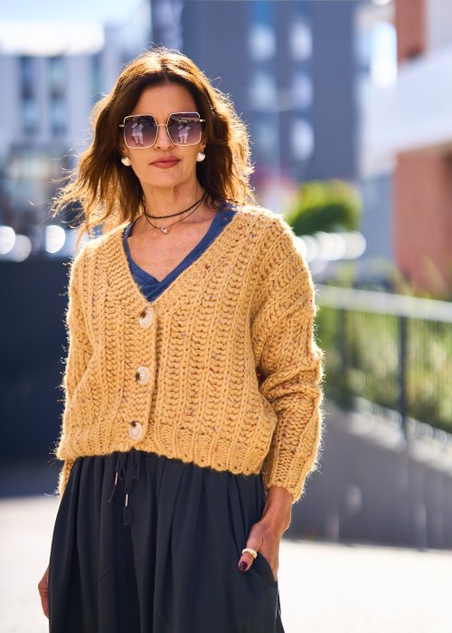 Żółty kardigan damski z grubym splotem, zapinany na duże guziki, o krótszym kroju i luźnym fasonie, styl casual boho