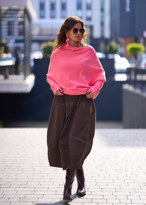 Jasnoróżowy sweter damski oversize o nietoperzowym kroju z asymetrycznym dołem, stylizacja miejska ze spódnicą.