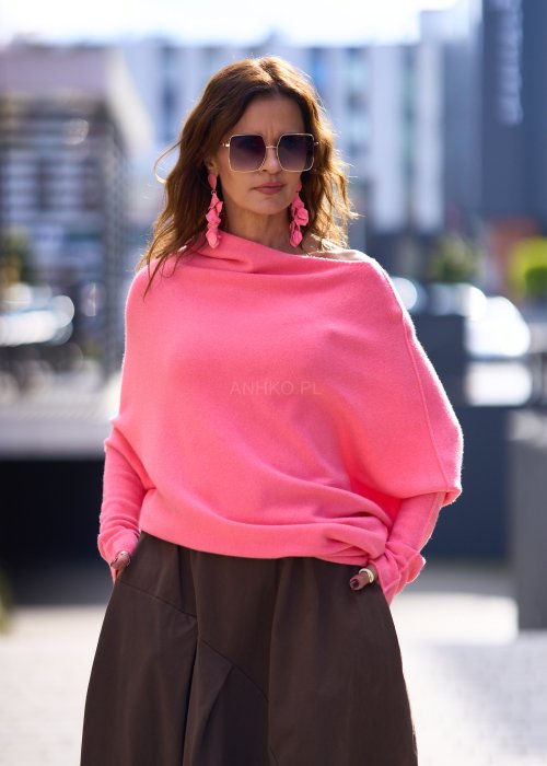 Jasnoróżowy sweter damski oversize o nietoperzowym kroju z asymetrycznym dołem, stylizacja miejska ze spódnicą.