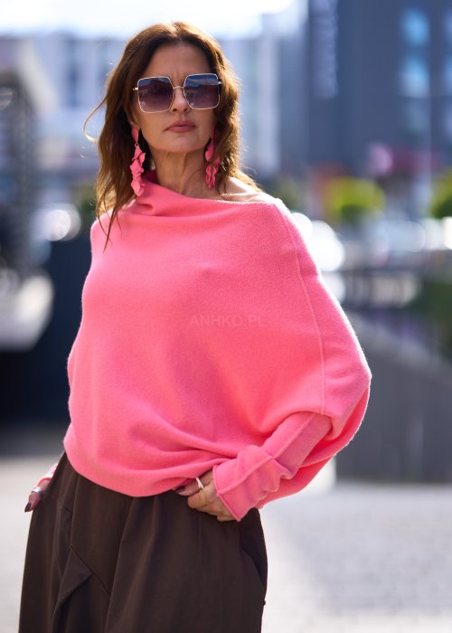 Jasnoróżowy sweter damski oversize o nietoperzowym kroju z asymetrycznym dołem, stylizacja miejska ze spódnicą.