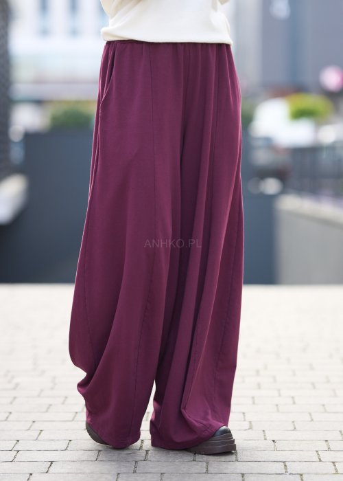Śliwkowe spodnie damskie o szerokich nogawkach z elastyczną talią, luźny fason w nowoczesnej stylizacji miejskiej.