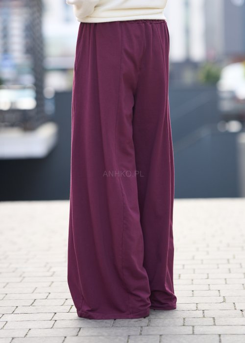 Śliwkowe spodnie damskie o szerokich nogawkach z elastyczną talią, luźny fason w nowoczesnej stylizacji miejskiej.