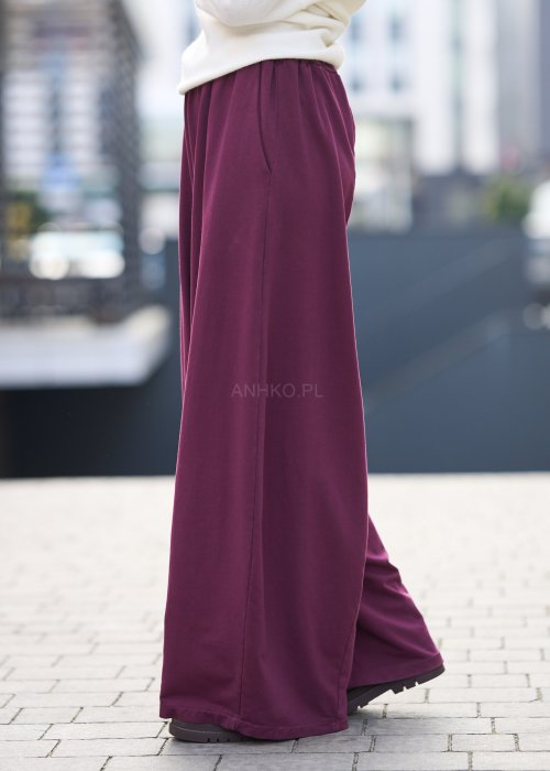 Śliwkowe spodnie damskie o szerokich nogawkach z elastyczną talią, luźny fason w nowoczesnej stylizacji miejskiej.