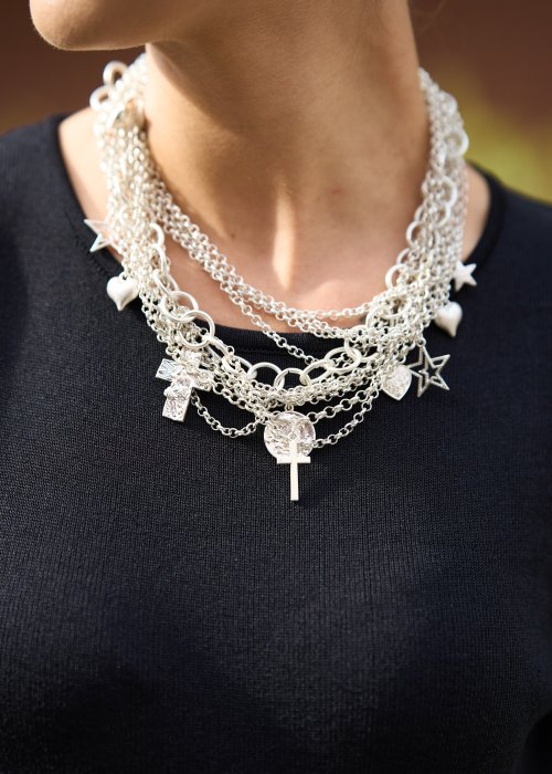 srebrnym naszyjnikiem z warstwowych łańcuszków i zawieszek w kształcie serc, gwiazd i krzyża