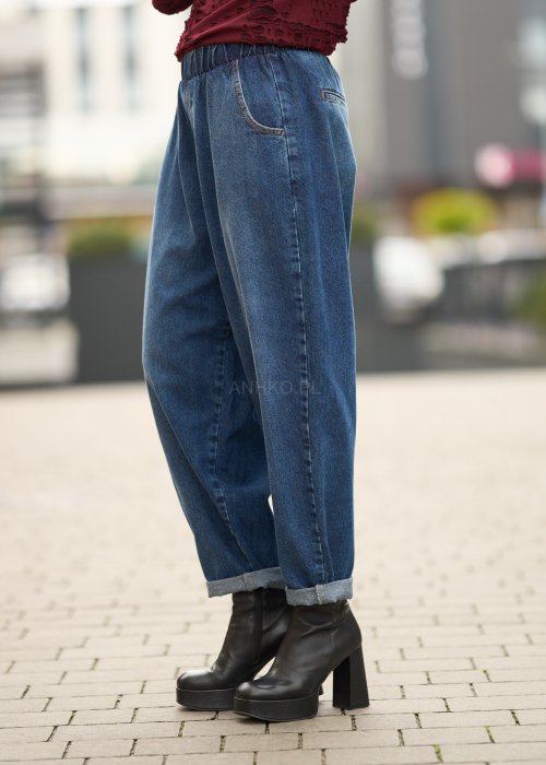 Niebieskie jeansy damskie o kroju slouchy z elastycznym pasem i podwiniętą nogawką. Stylizacja z botkami na obcasie w miejskim, casualowym stylu.