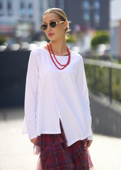 Biała bluzka damska z długim rękawem i wycięciem, w stylizacji z czerwoną spódnicą tiulową.