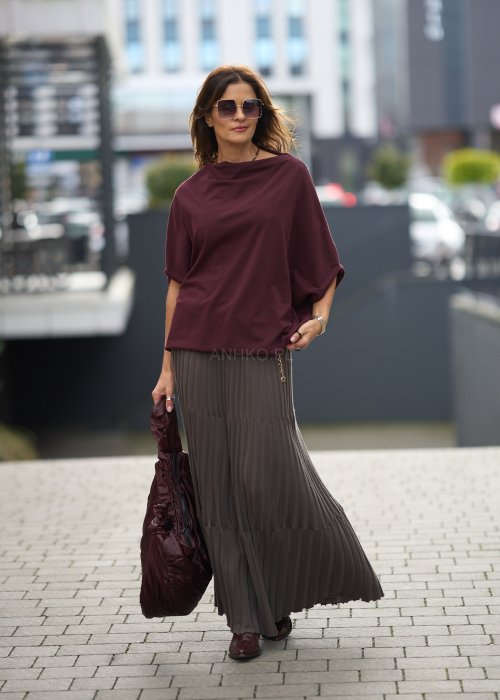 Śliwkowa bluzka damska oversize z rękawami typu nietoperz i szerokim dekoltem, zestawiona ze spódnicą w eleganckiej miejskiej stylizacji.