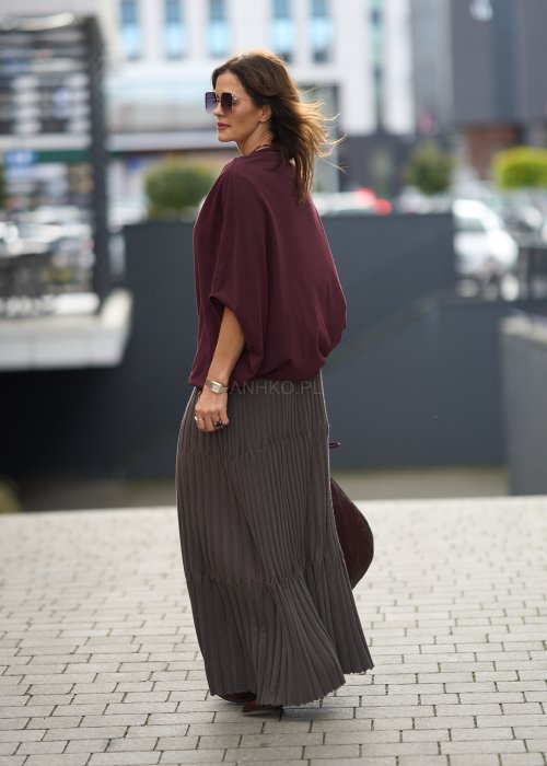 Śliwkowa bluzka damska oversize z rękawami typu nietoperz i szerokim dekoltem, zestawiona ze spódnicą w eleganckiej miejskiej stylizacji.