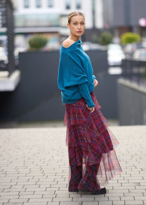 Morski sweter damski oversize o nietoperzowym kroju z asymetrycznym dołem, stylizacja miejska ze spódnicą w kratę.