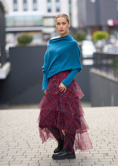 Morski sweter damski oversize o nietoperzowym kroju z asymetrycznym dołem, stylizacja miejska ze spódnicą w kratę.