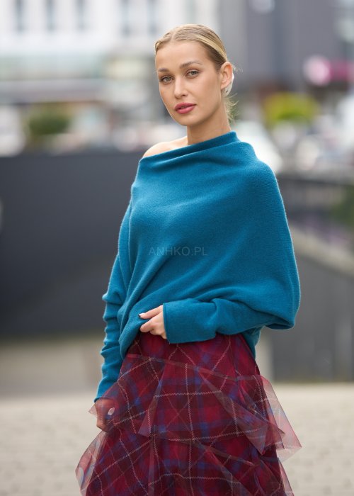 Morski sweter damski oversize o nietoperzowym kroju z asymetrycznym dołem, stylizacja miejska ze spódnicą w kratę.