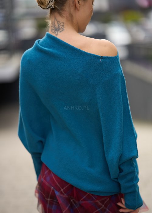 Morski sweter damski oversize o nietoperzowym kroju z asymetrycznym dołem, stylizacja miejska ze spódnicą w kratę.