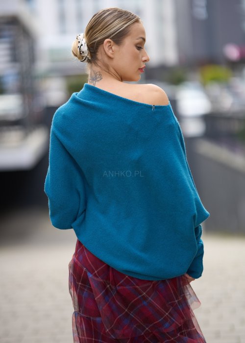 Morski sweter damski oversize o nietoperzowym kroju z asymetrycznym dołem, stylizacja miejska ze spódnicą w kratę.