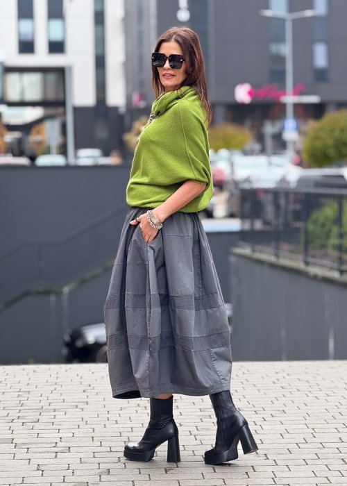 Grafitowa spódnica damska o kroju bombki z kieszeniami i dekoracyjnymi przeszyciami, pokazana w stylizacji z zielonym swetrem i czarnymi botkami na obcasie.