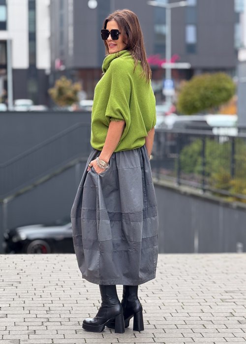 Grafitowa spódnica damska o kroju bombki z kieszeniami i dekoracyjnymi przeszyciami, pokazana w stylizacji z zielonym swetrem i czarnymi botkami na obcasie.