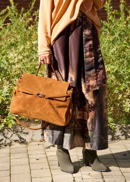 Karmelowa-torebka-z-zamszu-o-miekkiej-strukturze,-z-klapa-i-metalowym-zapieciem,-trzymana-w-dloni-kobiety-w-jesiennej-stylizacji-z-dluga,-wzorzysta-spodnica.-6.jpg