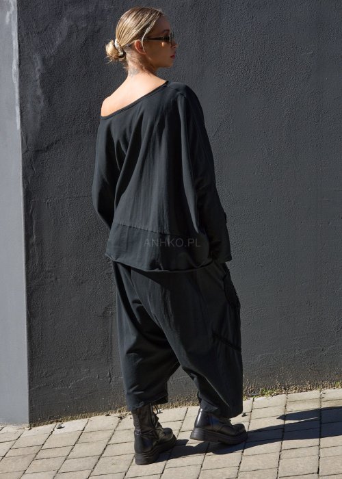 Czarne spodnie damskie oversize z obniżonym krokiem i ozdobnymi aplikacjami, zestawione z botkami i luźną bluzą w nowoczesnej stylizacji streetwear.