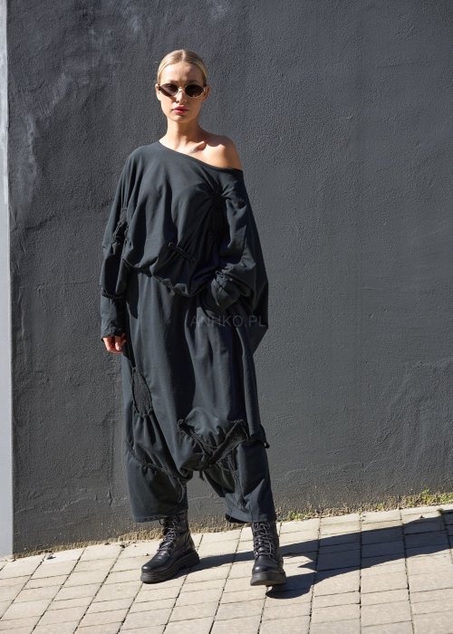 Czarne spodnie damskie oversize z obniżonym krokiem i ozdobnymi aplikacjami, zestawione z botkami i luźną bluzą w nowoczesnej stylizacji streetwear.